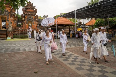 Bali, Endonezya - 30 Kasım 2023: Endonezya 'nın Bali kentindeki bir tapınak meydanında geleneksel beyaz giysiler giymiş bir grup birey.