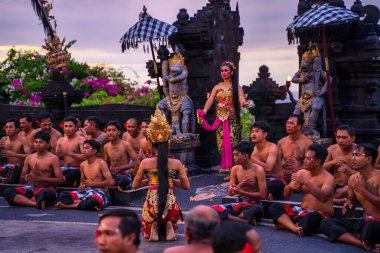 Bali, Indonesia - November 29, 2023: Traditional dancer's silhouette against twilight, surrounded by rhythmic chanters in ancient temple grounds clipart