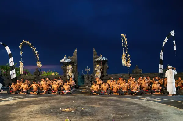 Bali, Endonezya - 23 Kasım 2023: Büyüleyici bir gece gösterisi Balili Kecak dansı, geleneksel kostümler ve bir tapınağa karşı yapılan ayinsel koreografi