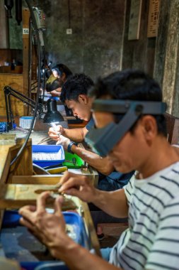 Bali, Endonezya - 22 Mart 2025: Zanaatkarlar ayrıntılı bir atölye ortamında ayrıntılı tasarımlar üzerinde ustalıkla çalışırlar, detaylara ve işçiliğe dikkat gösterirler.