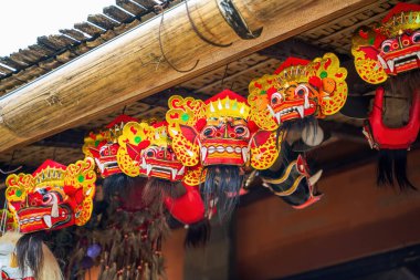 Canlı Balili Barong maskeleri bambu çatının altında asılı, Bali 'de geleneksel sanat ve kültür mirasını sergiliyor..