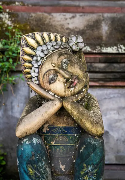 Dua eden kadın figürünün yıpranmış Balili heykeli elleri yüzünün altında birleşmiş şekilde duruyor. Süslü başlıkta altın aksanlar ve çiçek ayrıntıları yer alıyor.