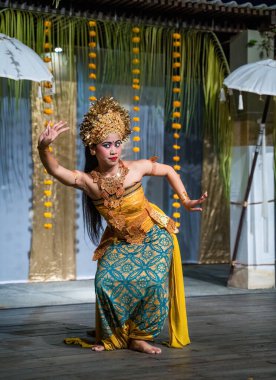 Bali, Endonezya - 11 Kasım 2023: Zarif Balili dansçı geleneksel Legong dansını ayrıntılı altın başlık, süslü takılar ve canlı mavi-sarı kostüm ile yapıyor.