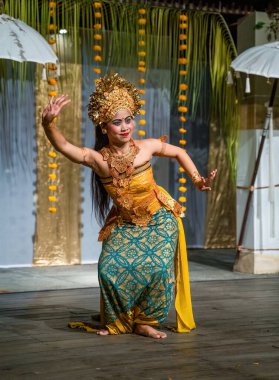 Bali, Endonezya - 11 Kasım 2023: Geleneksel Balili dansçı koreografisini sergiliyor. Anlamlı duruşu ve altın başlığı hareket ve sembolizm yoluyla kültürel hikaye anlatımını temsil ediyor..