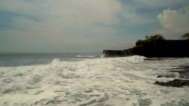 Bali 'deki Tanah Lot Tapınağı' nın kutsal kayalarına çarpan dalgaların yankısı, gün batımının altın ışığını yakalıyor.