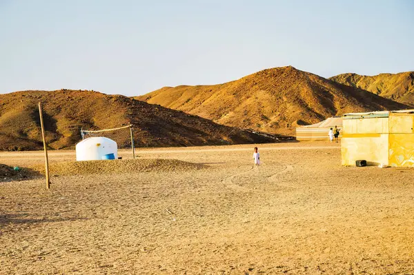 Kahire, Mısır - 11 Eylül 2023: Geleneksel beyaz yuvarlak konutlu çöl yerleşimi ve Mısır 'ın kurak topraklarında altın tepelere karşı modern binalar