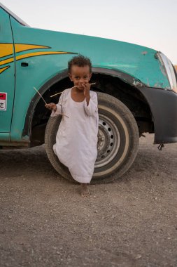 Kahire, Mısır - 11 Eylül 2023: Bir çöl ortamında yaşlı bir kamyonun yanında sakin bir şekilde duran genç bir çocuk kırsal ve sakin bir ortam sergilerken yakalandı..
