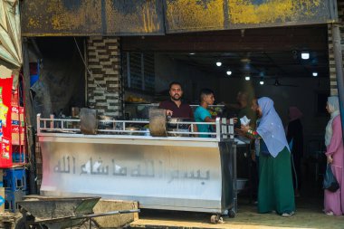 Kahire, Mısır - 11 Eylül 2023: Geleneksel bir Mısır pazarında insanları yakalayan hareketli bir gıda satıcısı sahnesi, canlı etkileşimleri ve kültürel atmosferi vurguluyor.