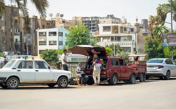 Kahire, Mısır - 11 Eylül 2023: Mısır 'da canlı bir sokak sahnesi yol kenarı satıcısı, klasik arabalar ve şehir binaları sergileniyor.