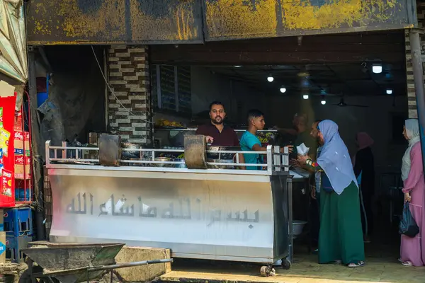 Kahire, Mısır - 11 Eylül 2023: Geleneksel bir Mısır pazarında insanları yakalayan hareketli bir gıda satıcısı sahnesi, canlı etkileşimleri ve kültürel atmosferi vurguluyor.