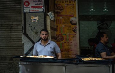 Kahire, Mısır - 9 Eylül 2023: Yerel gıda tezgahı sahibi geleneksel Orta Doğu mutfağını renkli menü sergisi ile servis ediyor