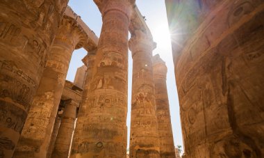 Mısır 'ın Luxor kentindeki Karnak Tapınağı' nın devasa taş sütunları, eski Mısır ihtişamının karmaşık hiyeroglifleriyle işlenmiş güneş ışığı altında parlıyor.