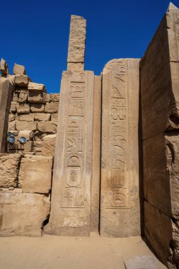 Towering ancient Egyptian obelisks covered in hieroglyphic inscriptions at Karnak Temple, Luxor, displaying millennia-old sacred texts and royal cartouches