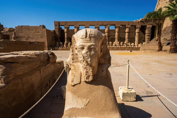 Древний египетский сфинкс статуя в историческом храме Луксор с колоннами руины на заднем плане, демонстрируя богатое наследие и архитектуру.