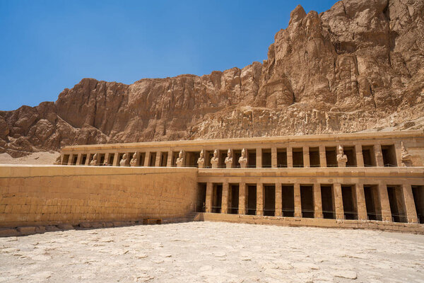Захватывающая колоннада храма Хатшепсут в морге со статуями Осириды на драматических известняковых скалах, демонстрирующих древнеегипетское величие