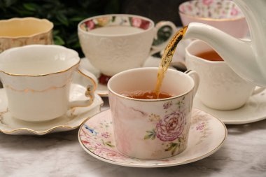 Porcelain tea cups with tea and slice of lemon with mint