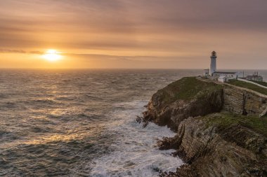 Rough weather off the lighthouse at sunset Isle of Anglesey North Wales