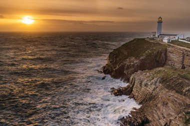 Rough weather off the lighthouse at sunset Isle of Anglesey North Wales