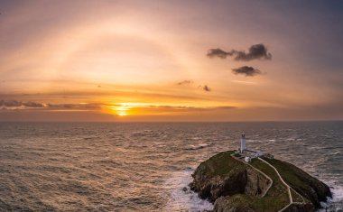 Rough weather off the lighthouse at sunset Isle of Anglesey North Wales