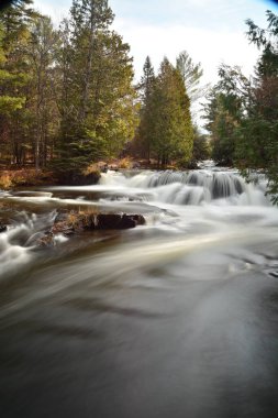 Michigan 'ın Yukarı Yarımadası' ndaki Ontonagon Nehri 'nin akan sularının güzel bir zaman gösterimi. Ekim manzarası en güzel günleri geride bıraktı. Ağaçlardaki yaprakların çoğu çoktan döküldü.. 