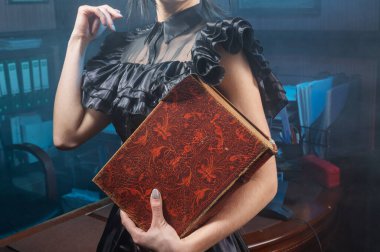 Old book in woman's hands close up. Woman holds an antique book in her hands. Closed book with aged pages.