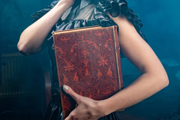 Old book in woman\'s hands close up. Woman holds an antique book in her hands. Closed book with aged pages.