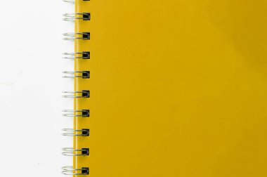 Close-up of a yellow notebook with checkered pages. Spiral notebook isolated