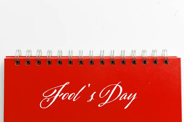 Red notebook with text FOOL\'S DAY on white background. Fool\'s day celebration concept