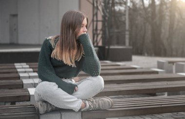 Parktaki bankta oturan üzgün genç kız. Açık havada bekâr bir kız. Yalnız üzgün kız