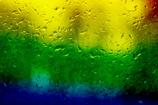 带彩虹色雨滴的玻璃杯 雨滴落在窗户上 美丽的彩虹背景 — 图库照片
