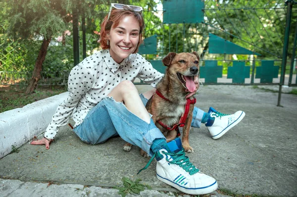 Animal shelter volunteer with dogs. Dog at the shelter. Lonely dogs in cage with cheerful woman volunteer