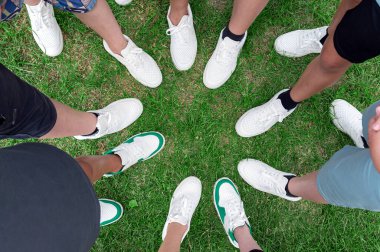 Arkadaşlar ayakkabılarını daire şeklinde birleştiriyor. Beyaz spor ayakkabılı gençler. 