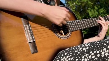 Akustik gitar çalan genç kız, yakın çekim. Kadın açık havada gitar akoru çalışıyor.. 