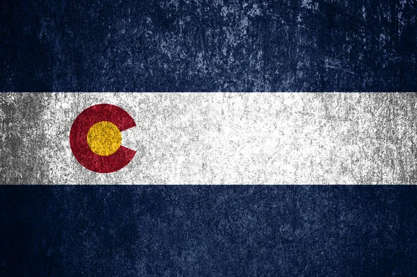 Close-up of the grunge Colorado state flag. Dirty Colorado state flag on a metal surface.