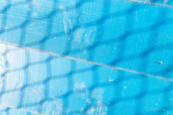 Blue wooden background with mesh shadow. Wood wall painted weathered blue . Vintage blue wood plank background.