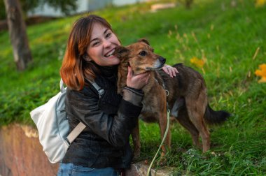 Melez köpeğini gezdiren genç bir kadın. Köpekli yaşam tarzı. Çok sevdiği köpeğine sarılan sıradan giysili çekici genç bir kadın.