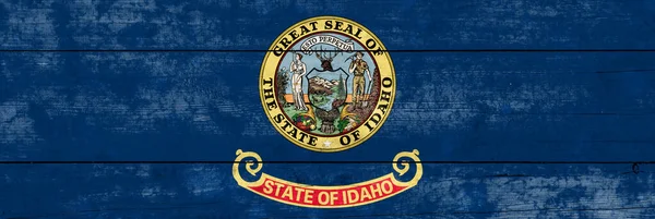 Idaho State flag on a wooden surface. Banner of the grunge Idaho State flag.