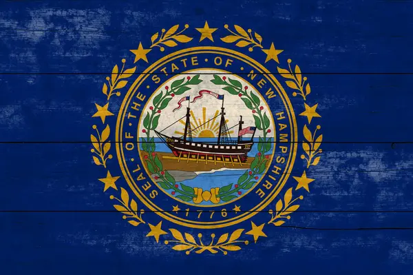 New Hampshire State flag on a wooden surface. Banner of the grunge New Hampshire State flag.