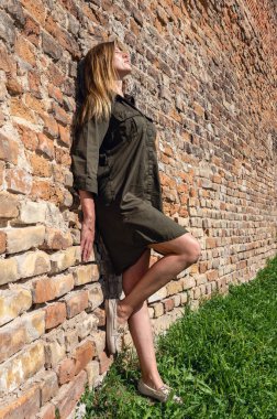 Antika şatonun taş duvarına poz veren güzel genç bir kadın. Ortaçağ harabelerinin arkasında poz veren kadın.