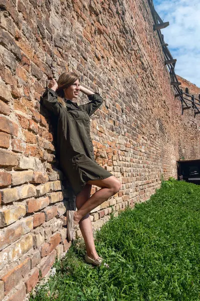Antika şatonun taş duvarına poz veren güzel genç bir kadın. Ortaçağ harabelerinin arkasında poz veren kadın.