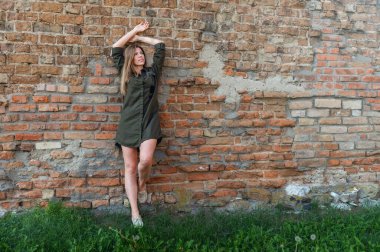 Antika şatonun taş duvarına poz veren güzel genç bir kadın. Ortaçağ harabelerinin arkasında poz veren kadın.