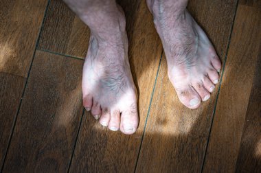 Bir adamın çıplak bacakları. Tahta zeminde çıplak erkek bacakları ve fotokopi alanı. Erkek çıplak ayak, uzun tırnaklı ayak parmakları.