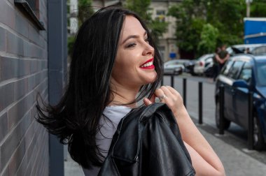 Güneşli bir günde dışarıda yürüyen genç bir kadın. Açık havada çekilmiş sevimli bir kadının portresi. Şık, genç ve çekici bir kadının güneşli bir hayat tarzı portresi.