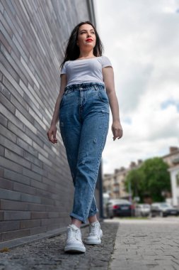 Güneşli bir günde dışarıda yürüyen genç bir kadın. Açık havada güzel bir kadının portresi. Şık, genç ve çekici bir kadının güneşli bir hayat tarzı portresi.