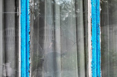 Evin penceresinde kırık camlar var. Dışarıda kırık cam pencere var.