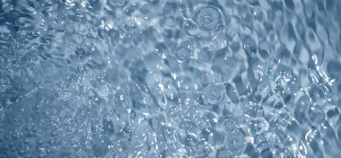 Dalgalı mavi su. Defocus, berrak, durgun su yüzeyi dokusunu su kabarcıkları ve kabarcıklarla bulanıklaştırdı. Su yüzeyi arkaplanı