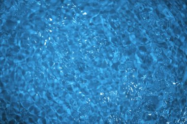 Dalgalı mavi su. Defocus, berrak, durgun su yüzeyi dokusunu su kabarcıkları ve kabarcıklarla bulanıklaştırdı. Su yüzeyi arkaplanı
