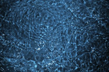 Dalgalı mavi su. Defocus, berrak, durgun su yüzeyi dokusunu su kabarcıkları ve kabarcıklarla bulanıklaştırdı. Su yüzeyi arkaplanı