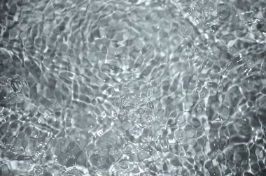 Dalgalı mavi su. Defocus, berrak, durgun su yüzeyi dokusunu su kabarcıkları ve kabarcıklarla bulanıklaştırdı. Su yüzeyi arkaplanı