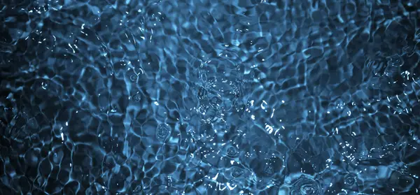 Dalgalı mavi su. Defocus, berrak, durgun su yüzeyi dokusunu su kabarcıkları ve kabarcıklarla bulanıklaştırdı. Su yüzeyi arkaplanı